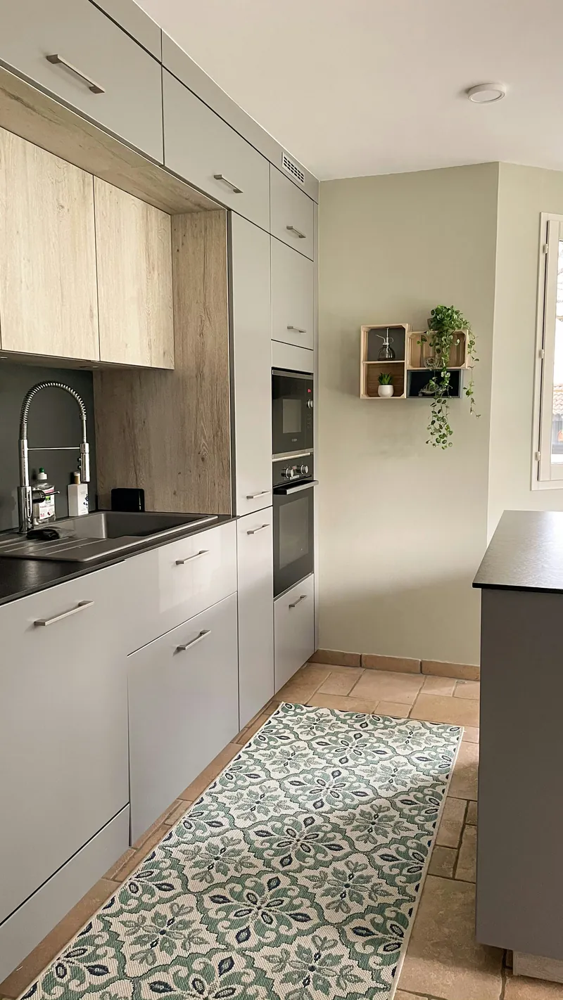 Compact grey handleless kitchen with an oak accent panel, a built-in oven and microwave column and dark worktops